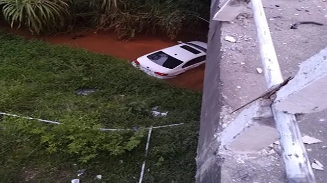 Carro bate em ponte e cai em riacho