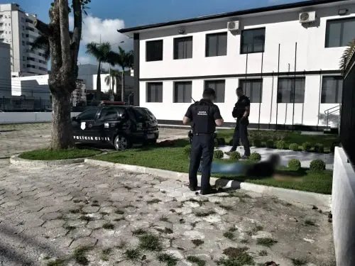 Homem usa o teto de uma viatura da pol&iacute;cia para preparar droga para uso