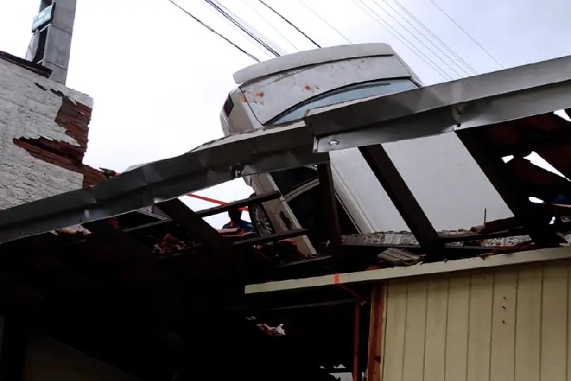  Carro capota e fica preso no telhado