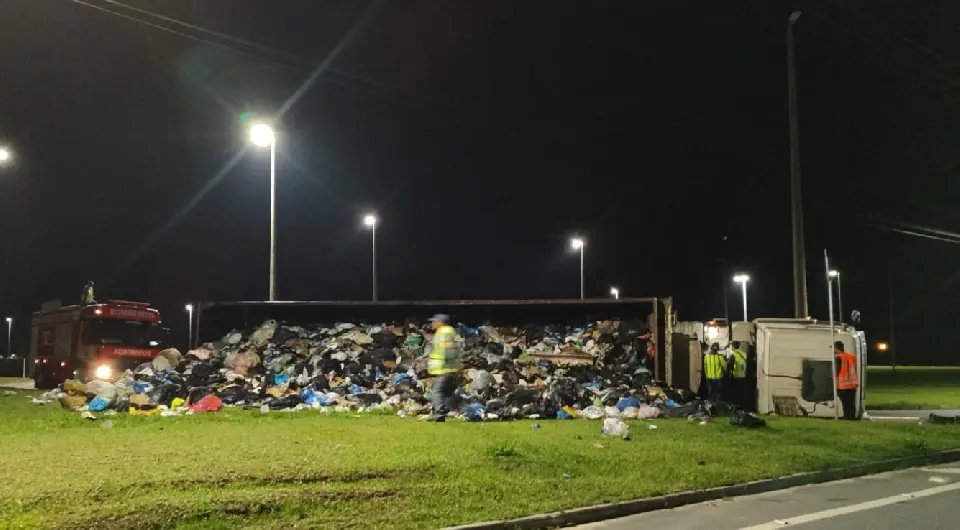 Carreta com lixo reciclável tomba em trevo durante a madrugada