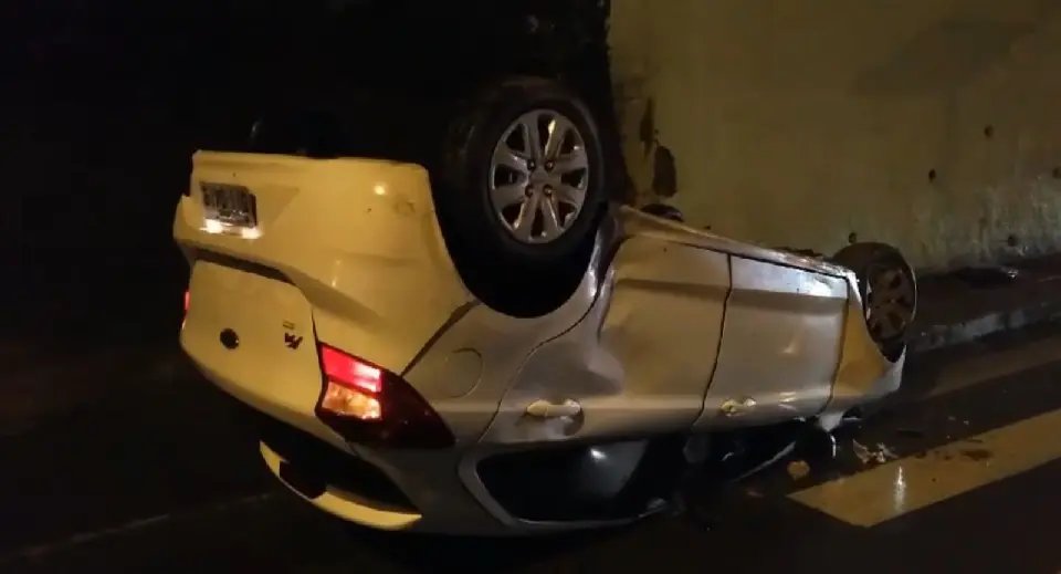 Carro bate em lateral de carreta estacionada e capota