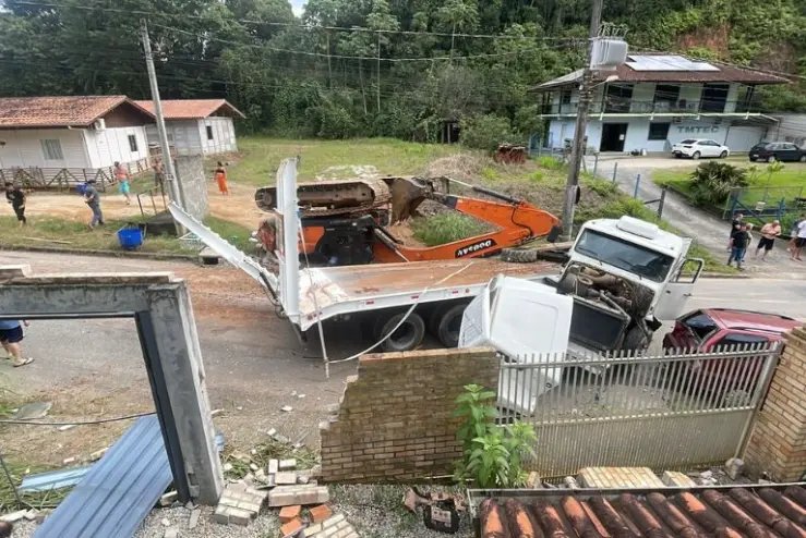 Máquina cai de carreta e atinge muro e veículo no Souza Cruz