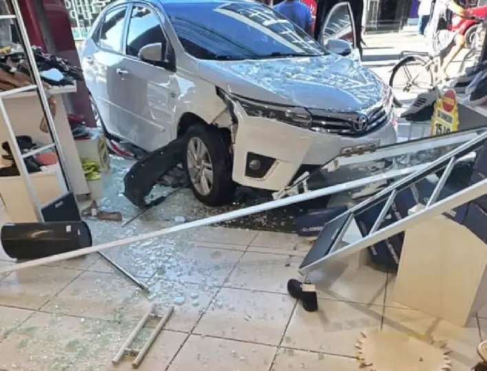 Carro atinge vitrine de loja após colisão com caminhão
